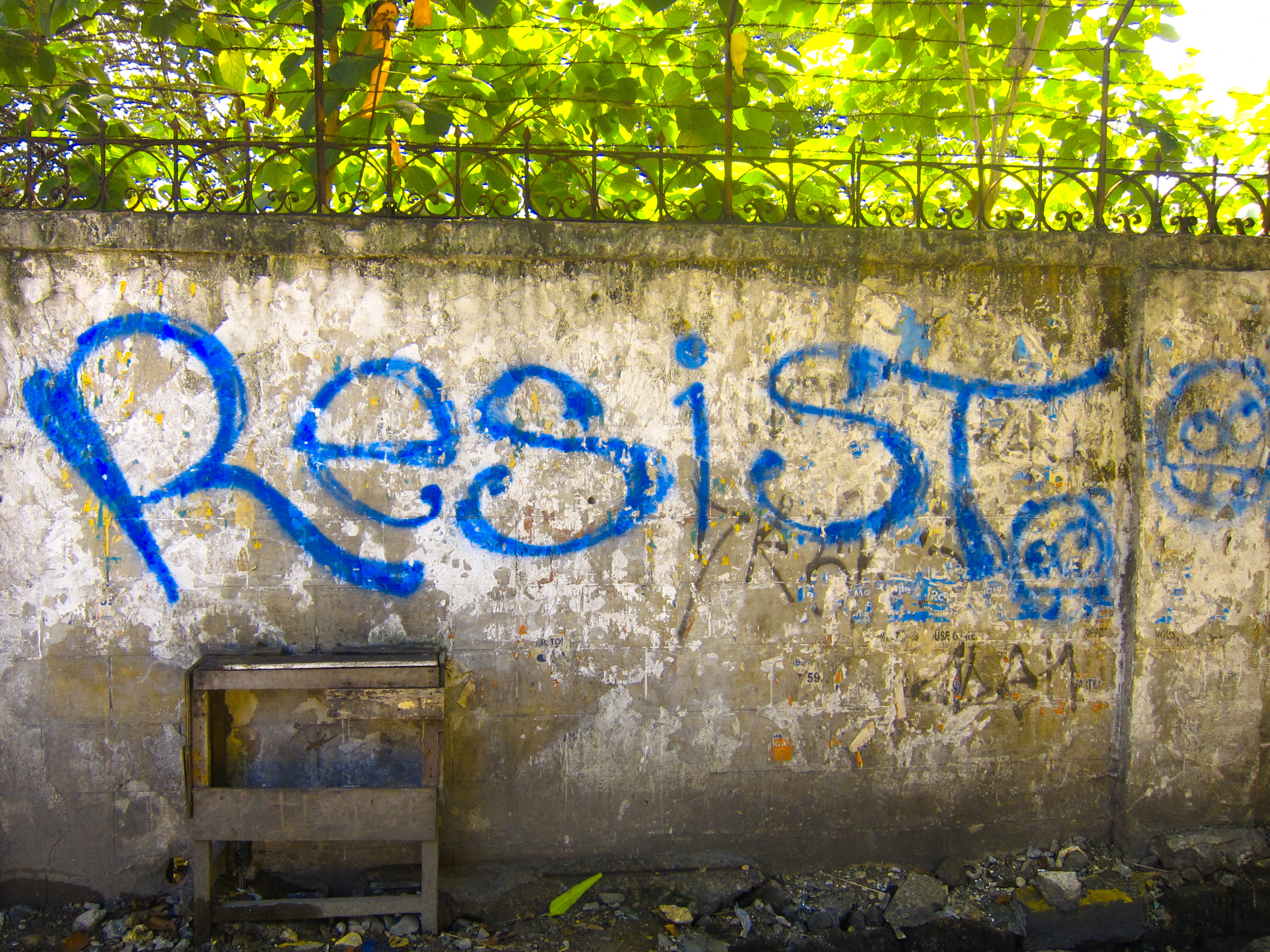 blue graffiti on a faded gray wall that sas resist